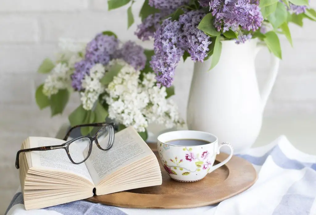 coffee next to open book and flowers
